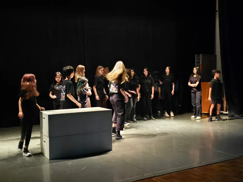 A group of people are standing on a stage in a dark room.