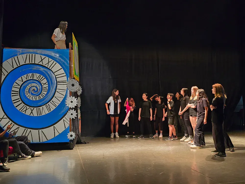 A group of people are standing on a stage in front of a spiral clock.