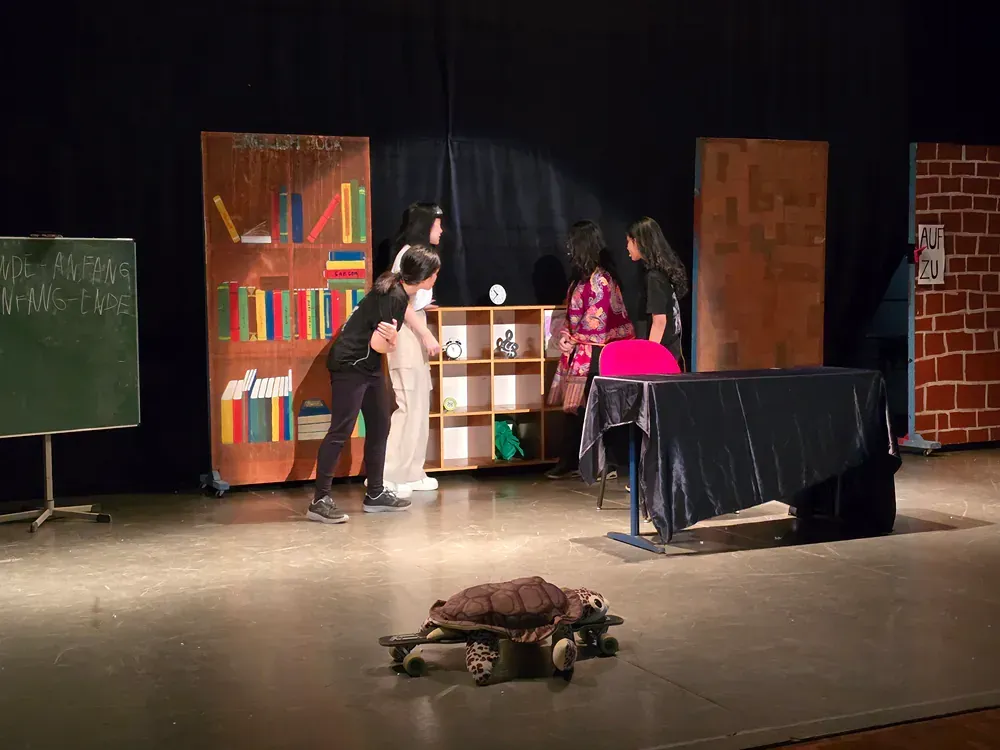 A group of people are standing on a stage in front of a bookshelf.