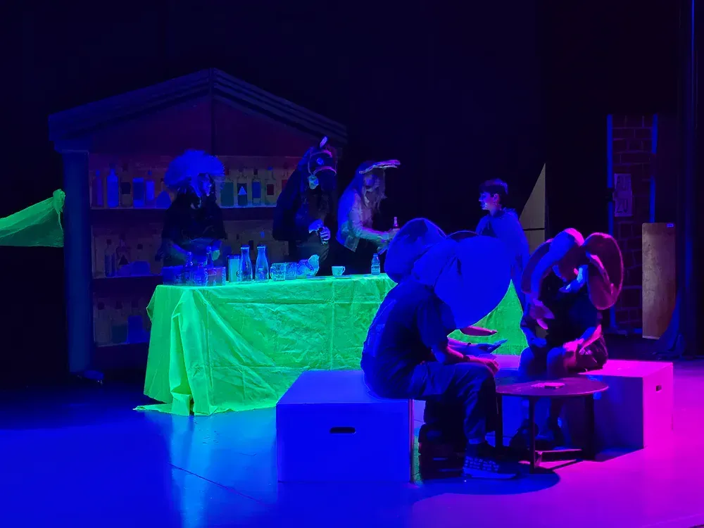 A group of people are sitting on boxes on a stage in front of a table.