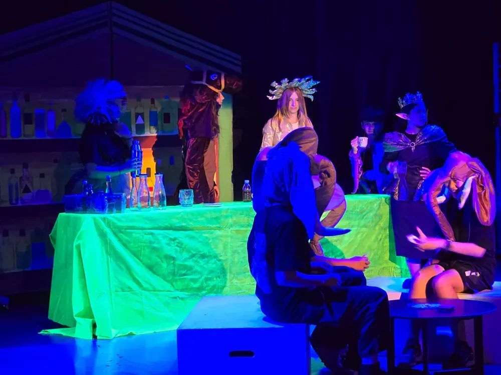 A group of people are sitting around a table on a stage.
