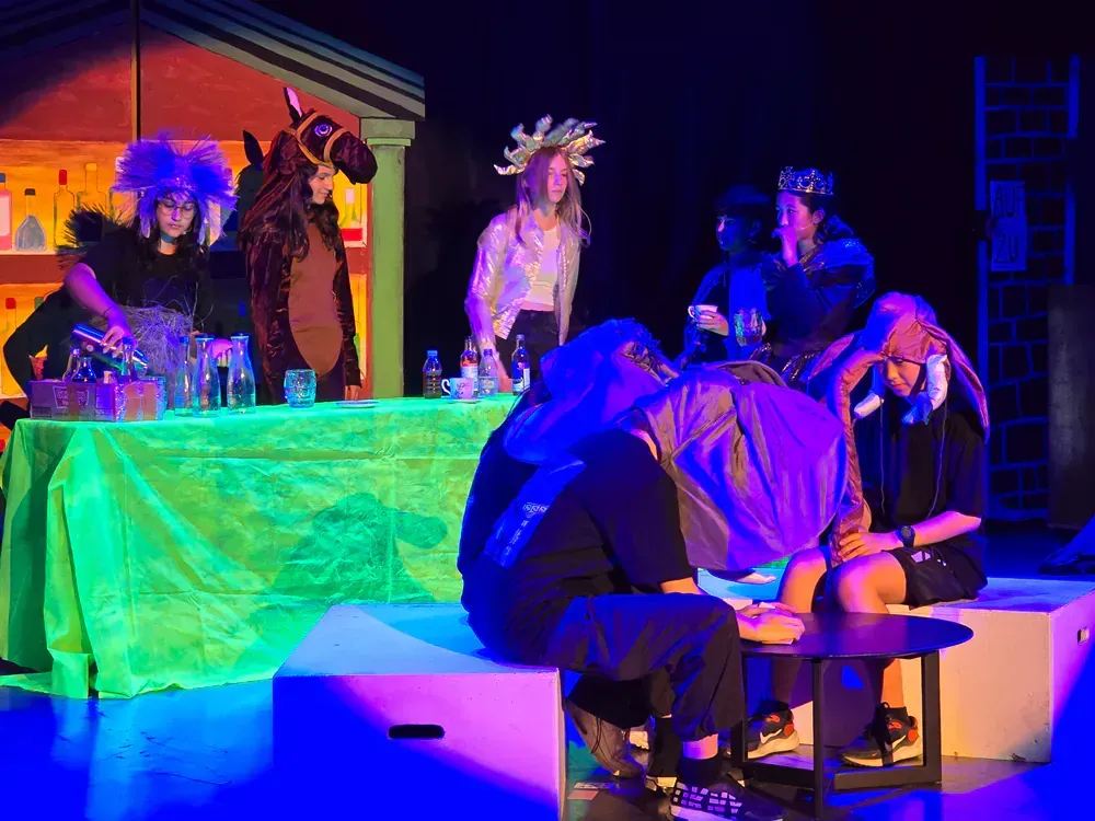 A group of people are sitting around a table on a stage.