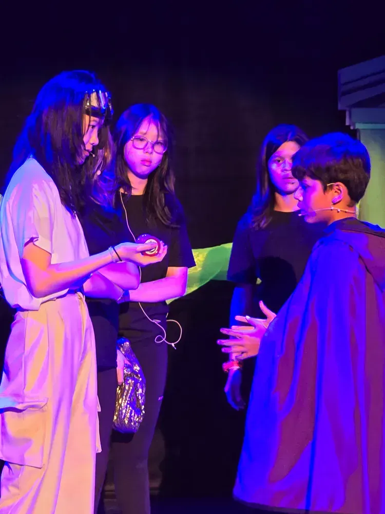 A group of people are standing on a stage under purple lights.