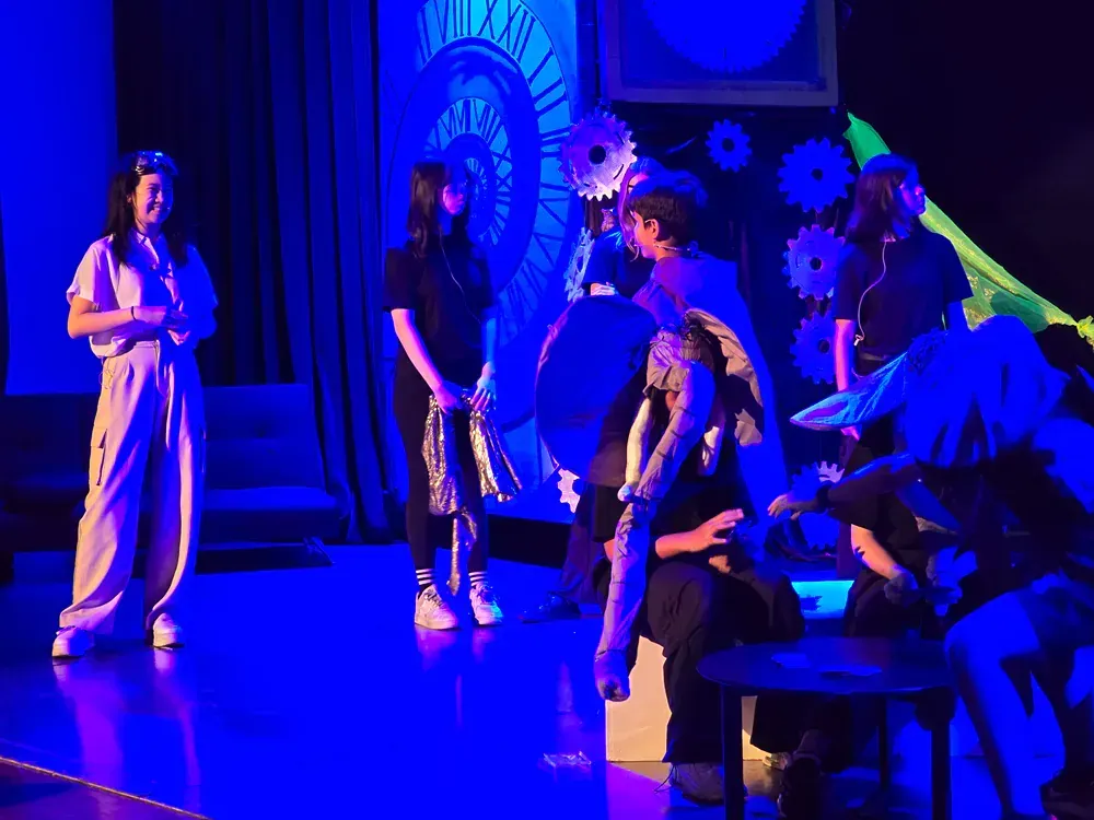 A group of people are standing on a stage in front of a clock.