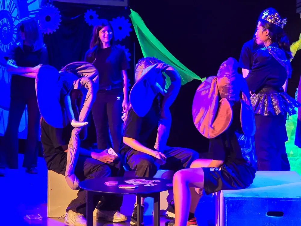 A group of people are sitting around a table in a dark room.