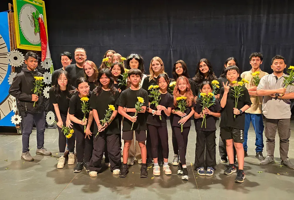 A group of people standing on a stage holding flowers.