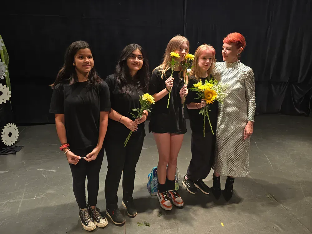 A group of girls are standing next to each other on a stage holding flowers.