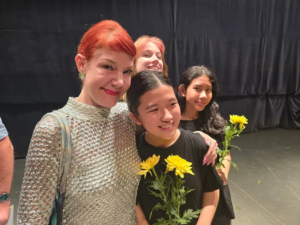 A group of young girls are posing for a picture while holding yellow flowers.