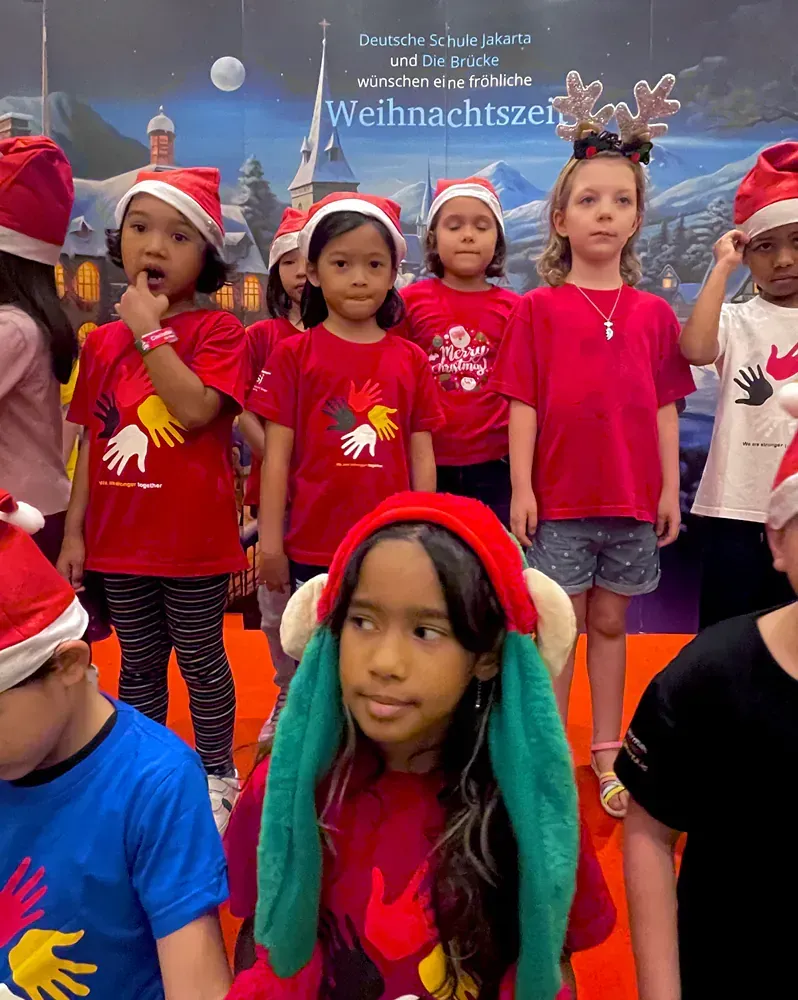 A group of children wearing santa hats and red shirts