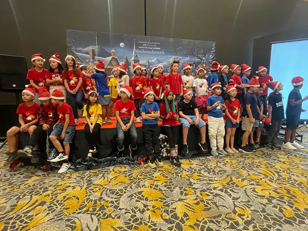 A group of children wearing santa hats are posing for a picture.