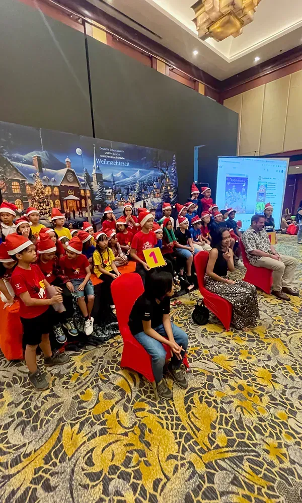 A group of people wearing santa hats are sitting in a room.