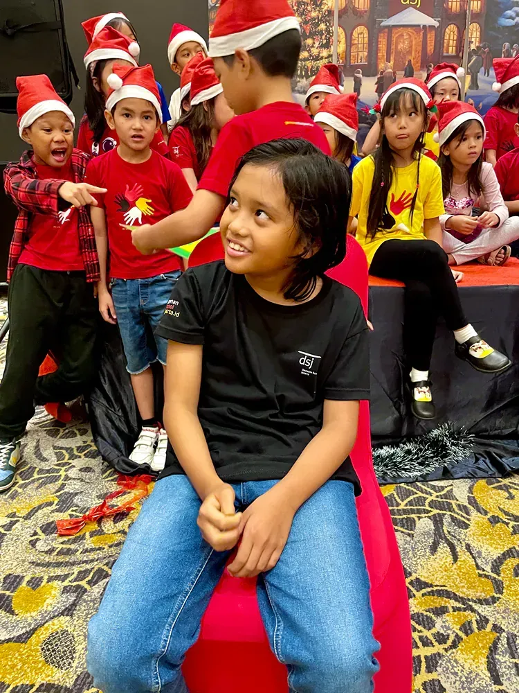 A group of children wearing santa hats are sitting in a room.
