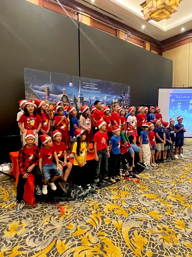 A group of children wearing santa hats are posing for a picture in a room.