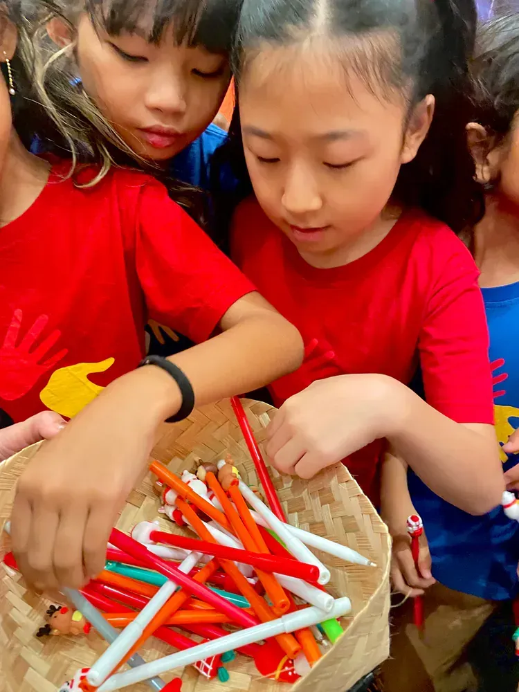 A group of young girls are looking at a basket of pens.