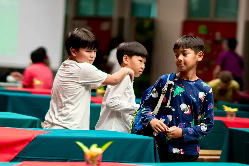 Three young boys are standing next to each other in a room.