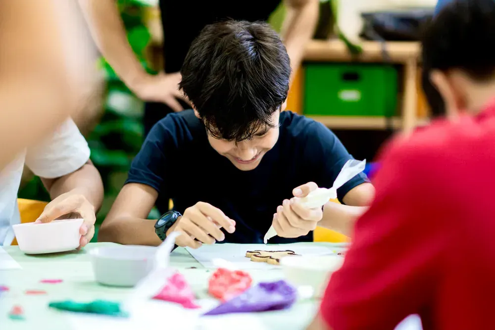 A group of children are sitting at a table making crafts.