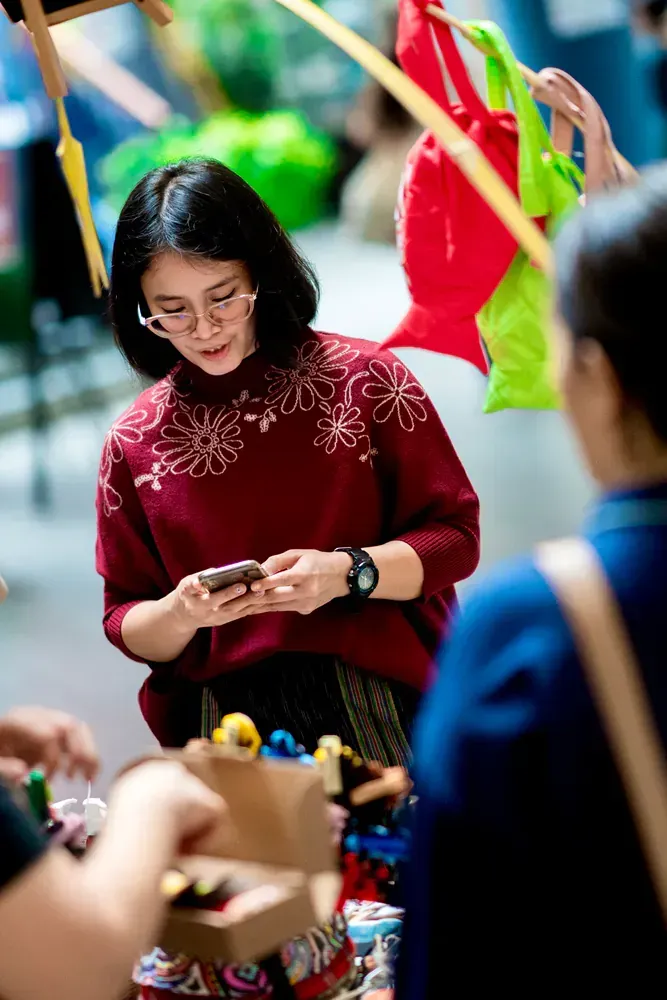 A woman in a red sweater is looking at her phone.