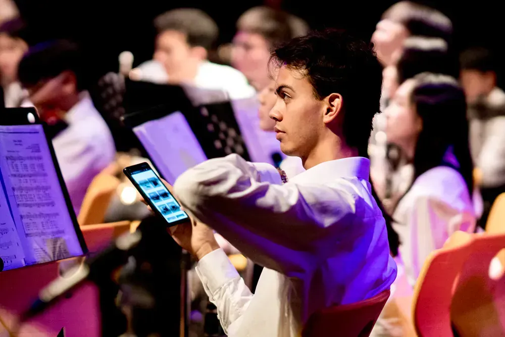 A young man is using a cell phone in an orchestra.