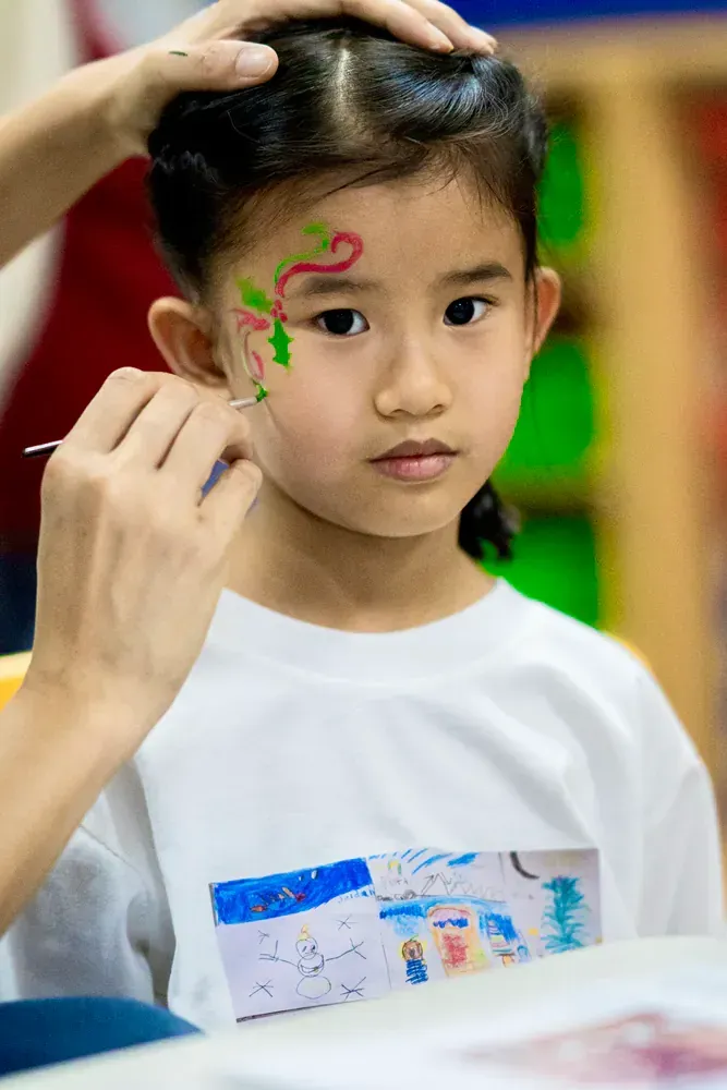 A little girl is getting her face painted for christmas.