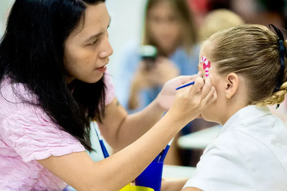 A woman is painting a girl 's face with a brush.