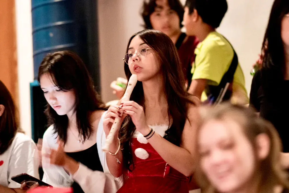 A girl is playing a flute in a crowd of people.