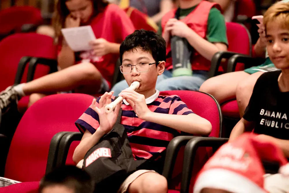 A boy is playing a flute in a crowd of people