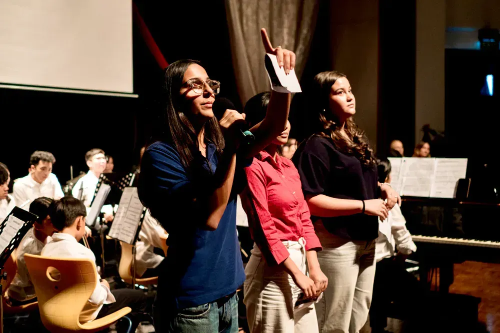 A group of people standing in front of an orchestra on a stage