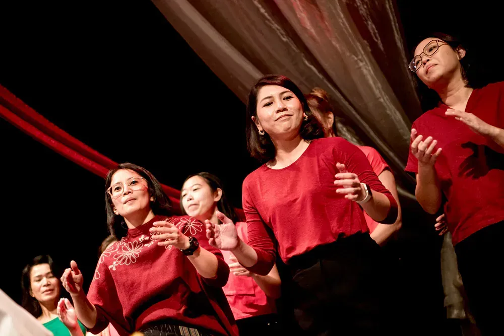 A group of women in red shirts are dancing on a stage.