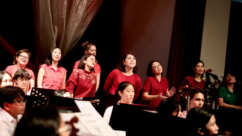 A group of people are singing in a choir on a stage.