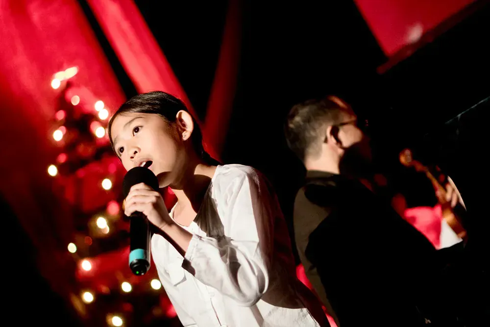 A young girl is singing into a microphone on a stage.