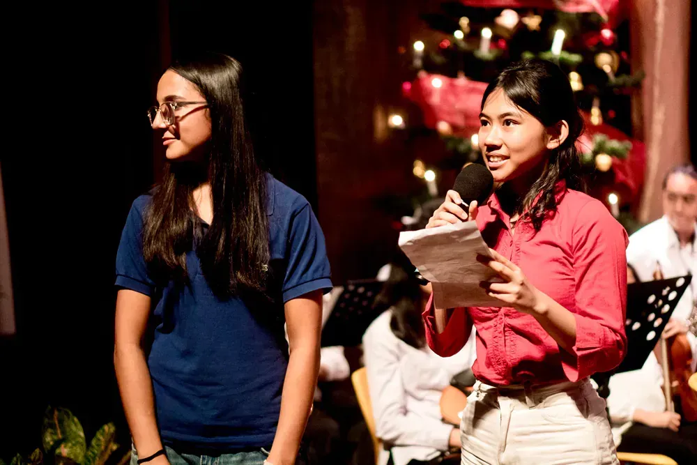 Two women are standing next to each other on a stage holding microphones.