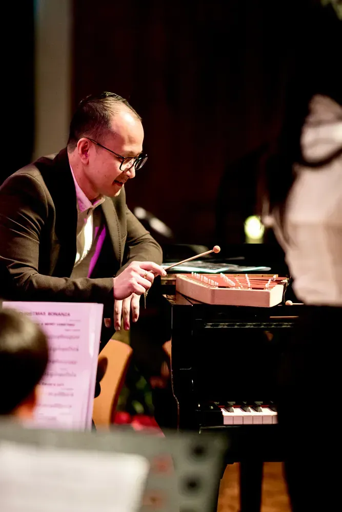 A man in a suit is playing a piano on a stage.