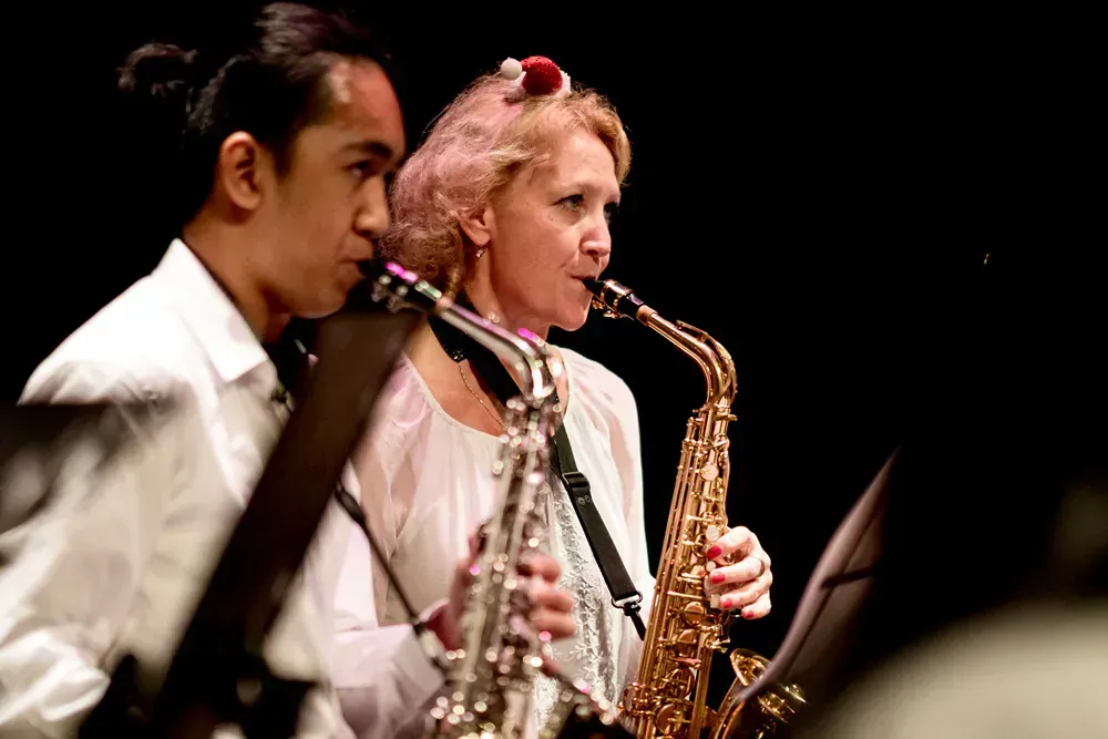 A man and a woman are playing saxophones on a stage.