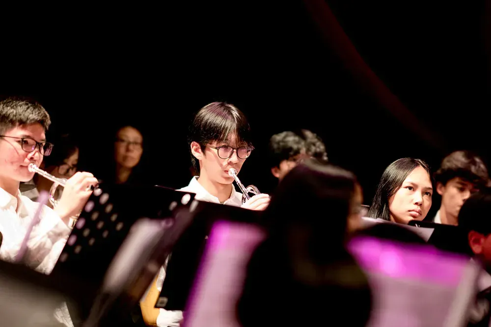 A group of people are sitting in a dark room playing instruments.