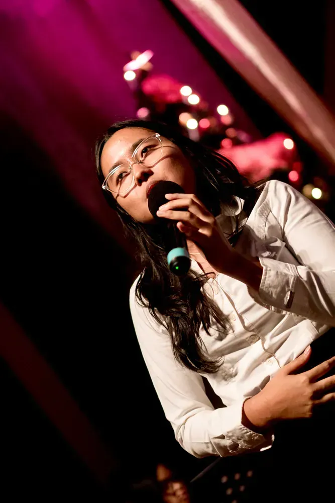 A woman is singing into a microphone on a stage.