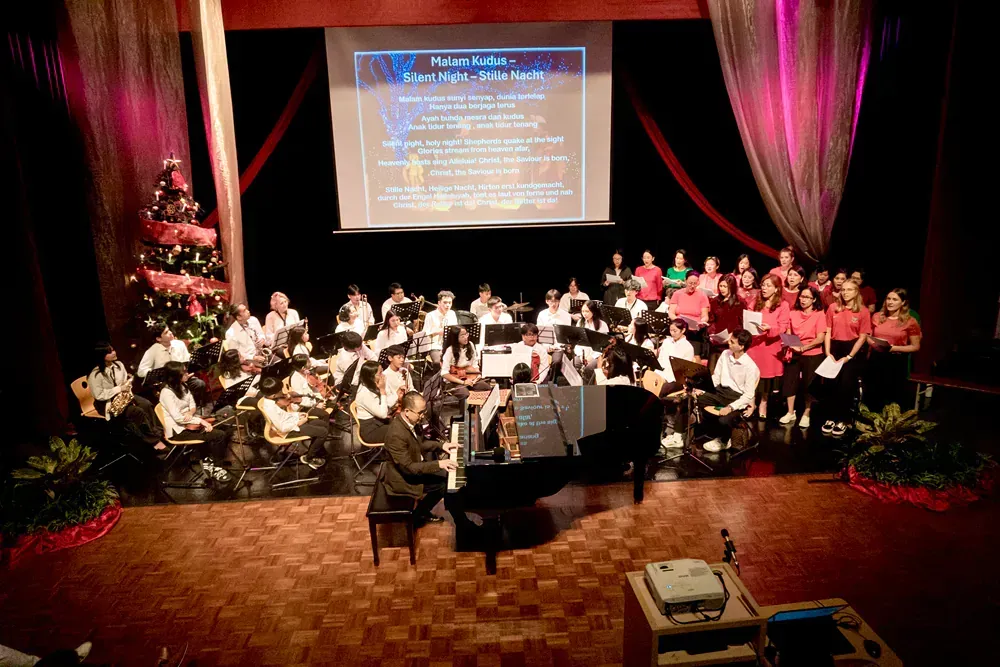 A man playing a piano in front of a large choir on a stage