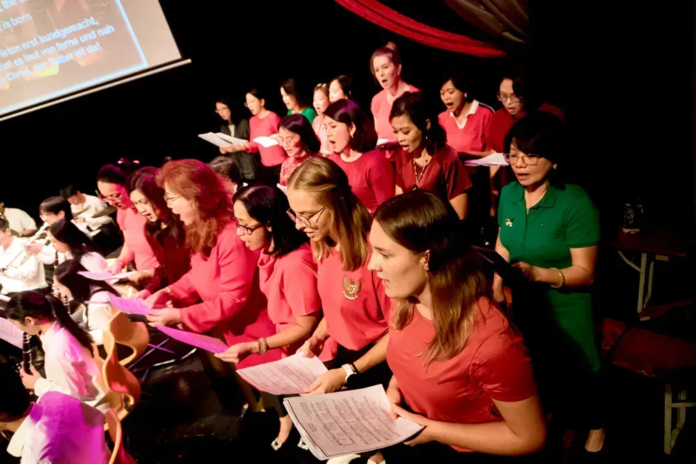 A group of women in red shirts are singing in a choir.