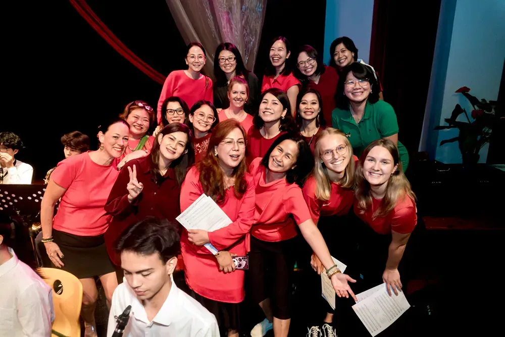 A group of people in red shirts are posing for a picture on a stage.