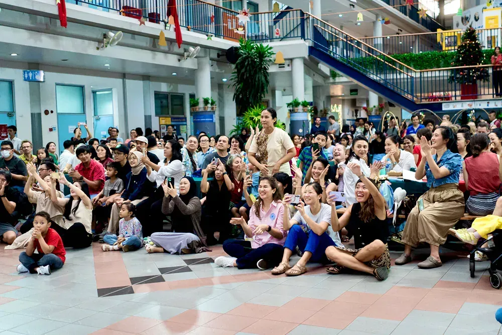A large group of people are sitting on the floor in a building.