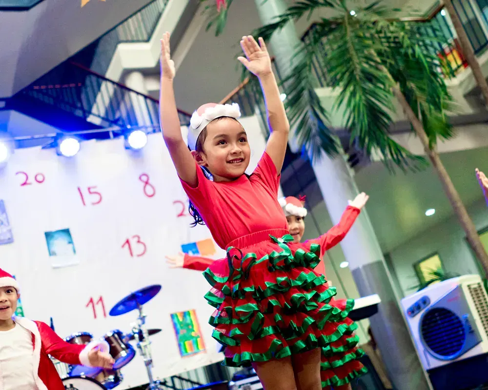A little girl in a christmas dress is dancing on stage