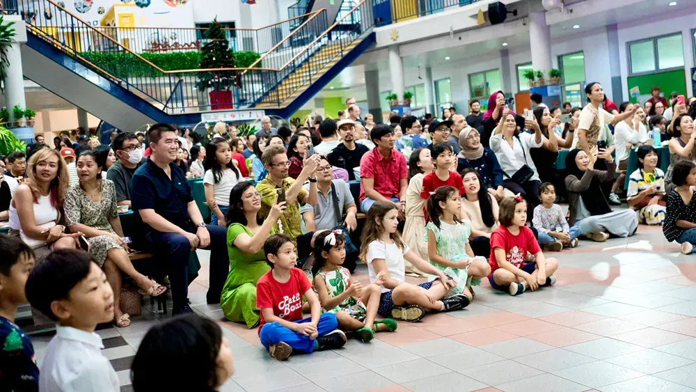 A large group of people are sitting on the floor watching a performance.