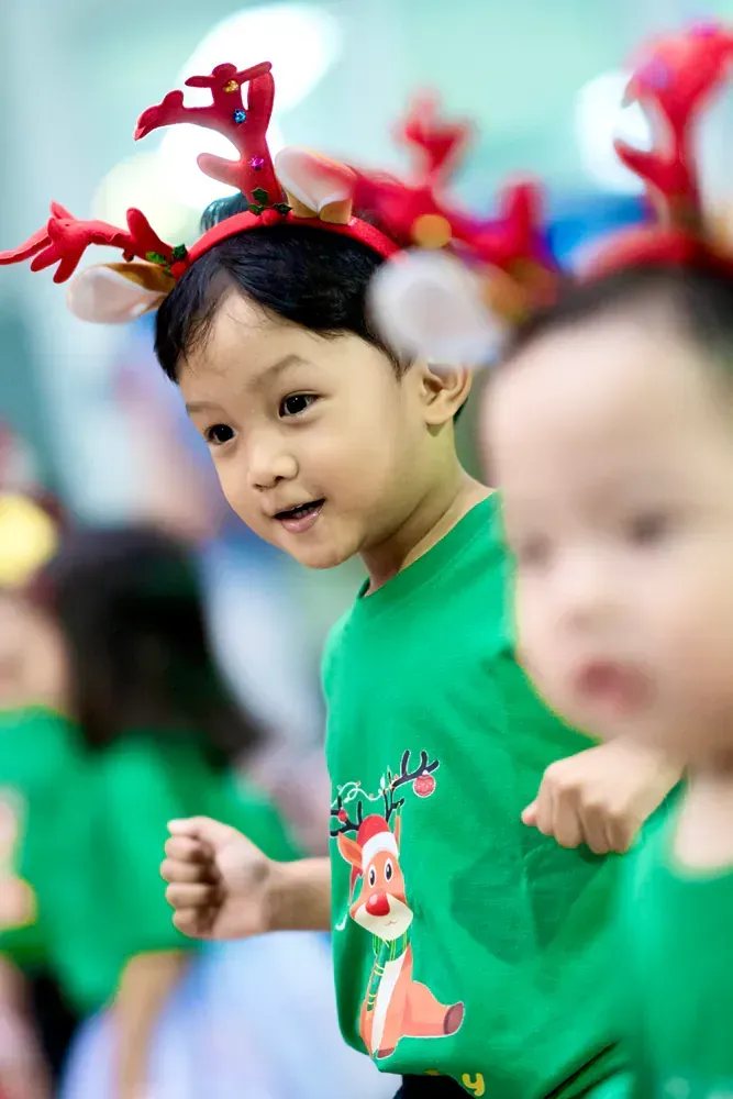 A group of children wearing reindeer antlers and green shirts