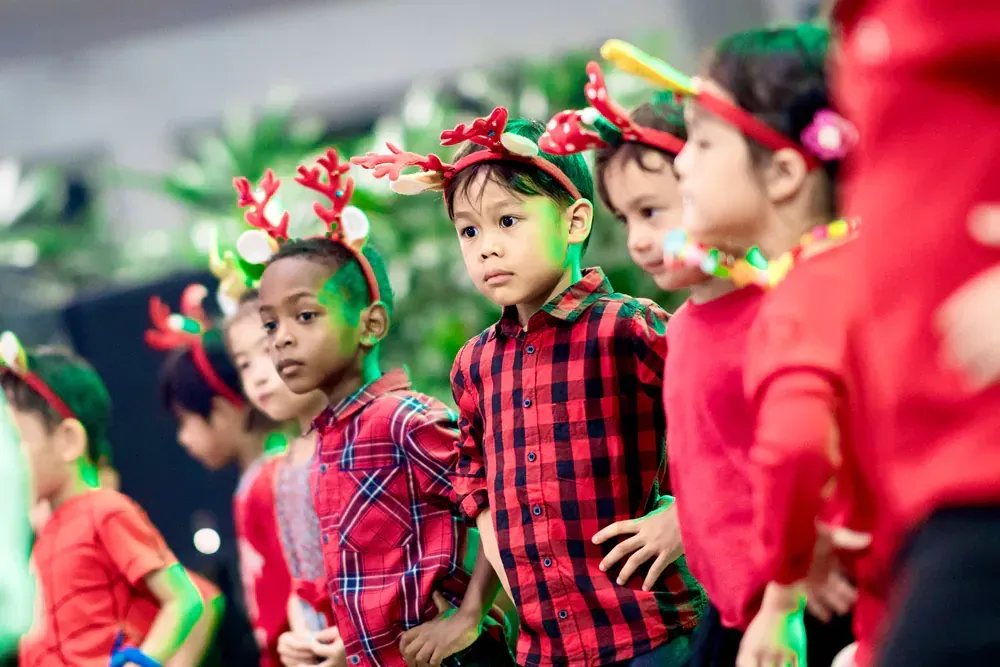 A group of children wearing reindeer antlers are standing in a line.
