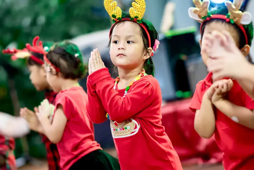 A group of young children wearing christmas costumes are dancing together.
