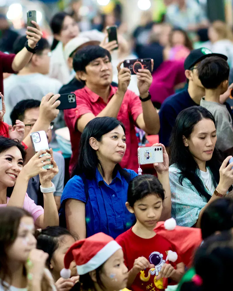 A crowd of people are taking pictures with their phones.