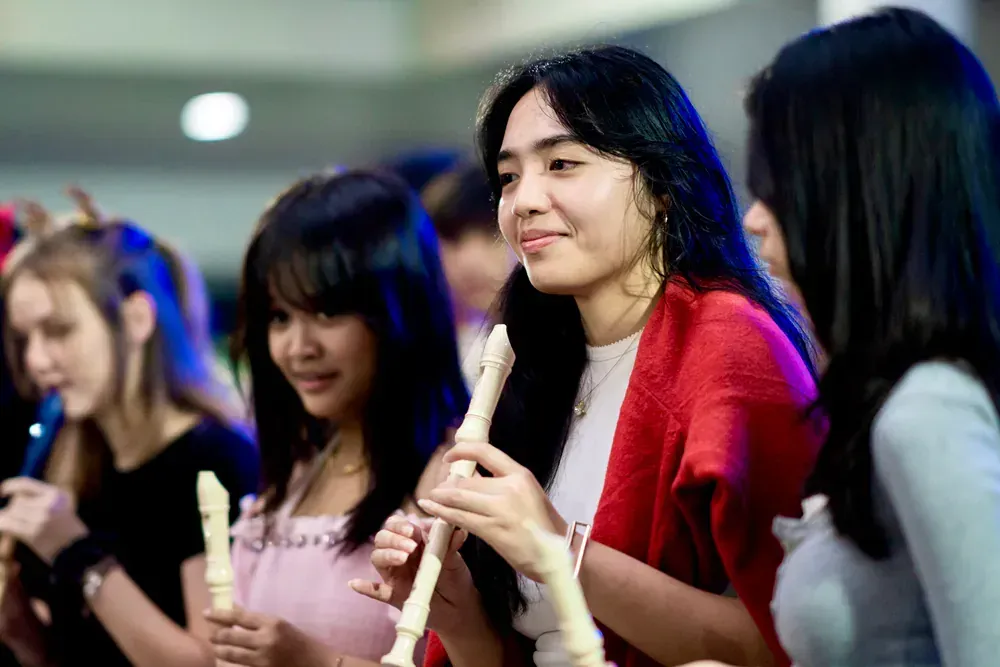 A group of young women are playing a recorder in a room.