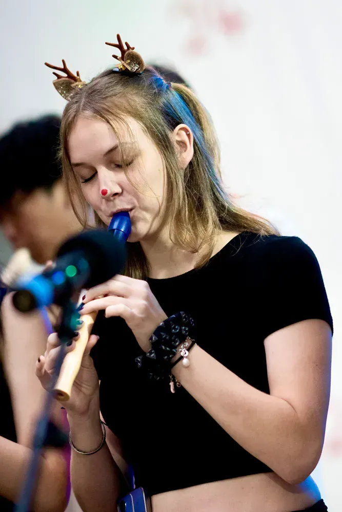 A woman with antlers on her head is playing a flute