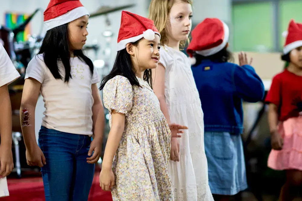 A group of young girls wearing santa hats are standing next to each other.