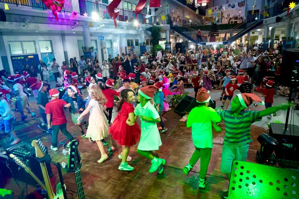 A group of children are dancing on a stage at a christmas party.