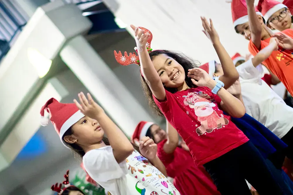 A group of children are wearing santa hats and dancing together.
